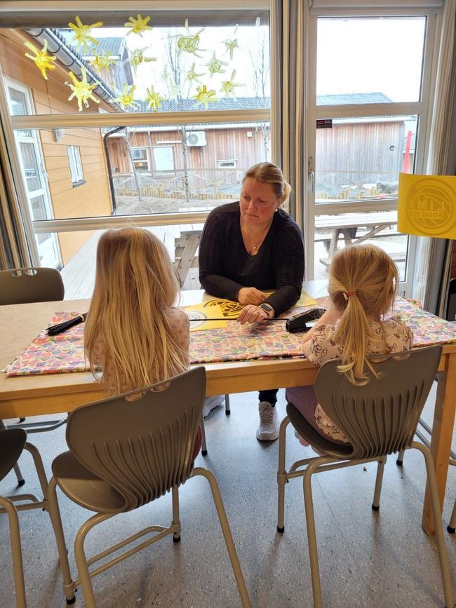 En voksen og to barn sitter ved formingsaktivitet ved bord