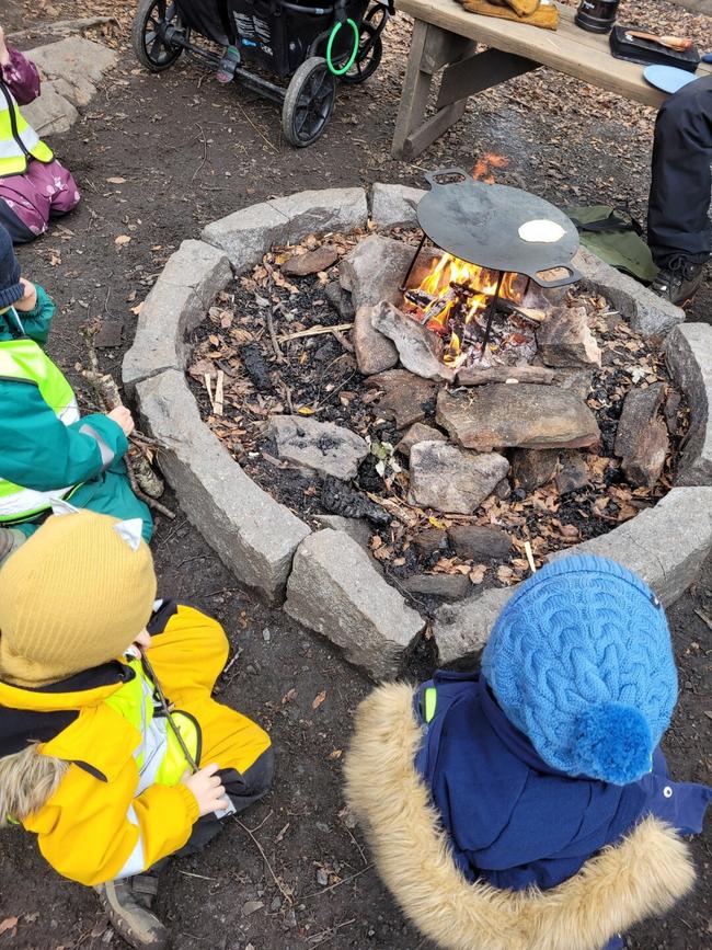 barn sitter rundt bål som er laget med stein rundt