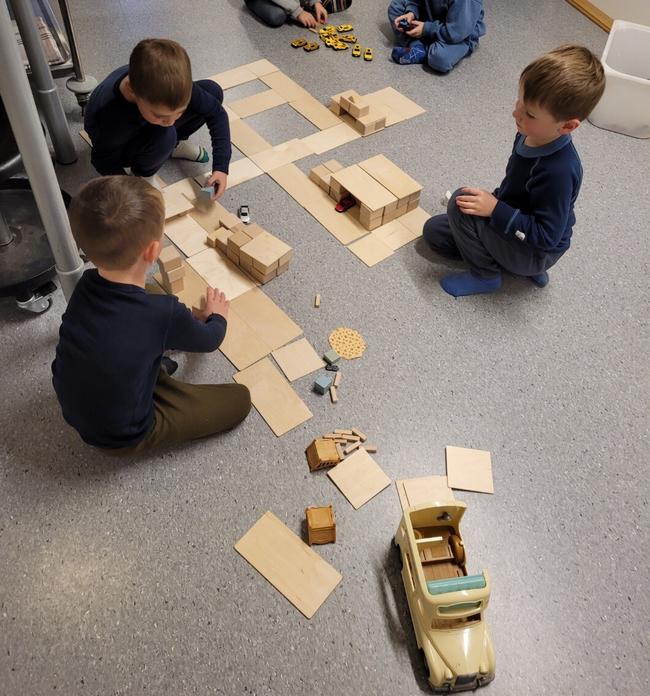 tre barn lager bilveier med trebiter og klosser