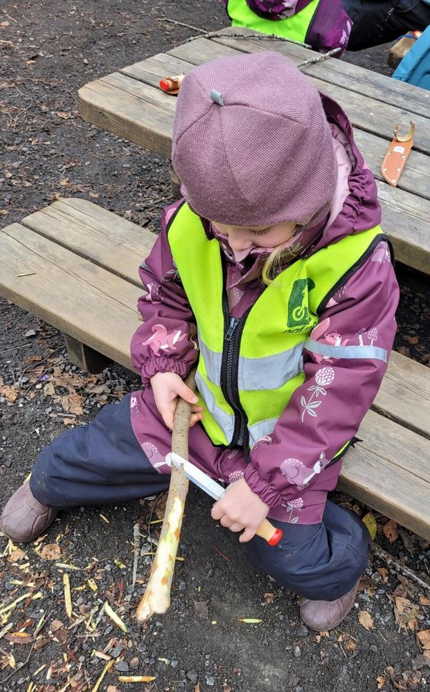 Et barn spikker med kniv på en kvist