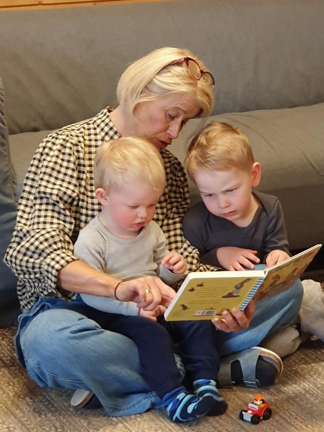 En voksen har to barn på fanget og de leser i ei bok